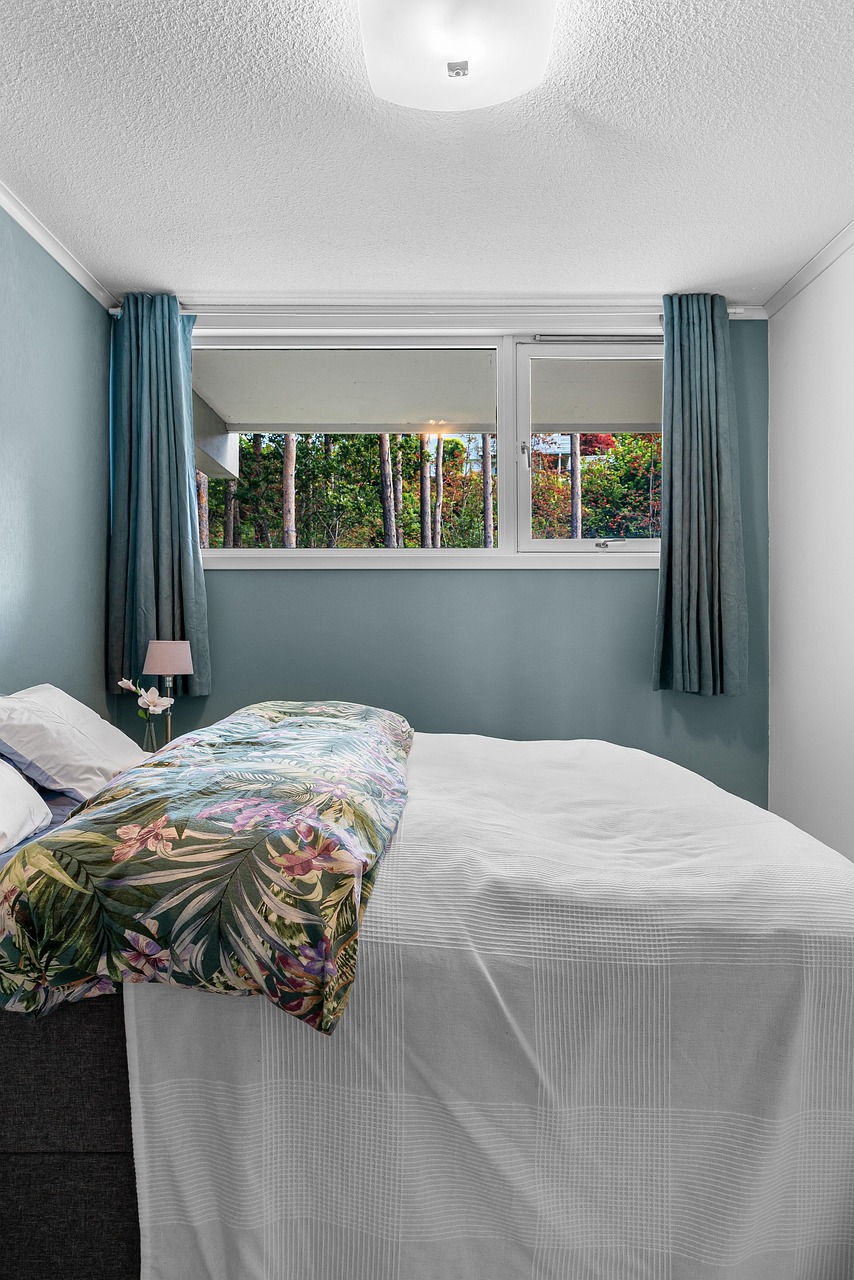 Bedroom with a muted green accent wall and simple bedside styling
