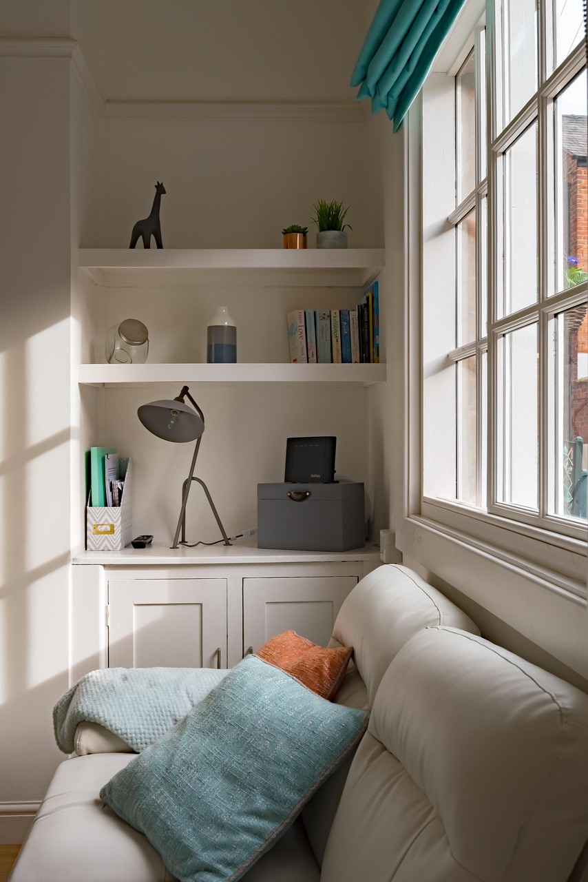 Reading nook with a couch pulled up beside a sunny window and sheer curtains