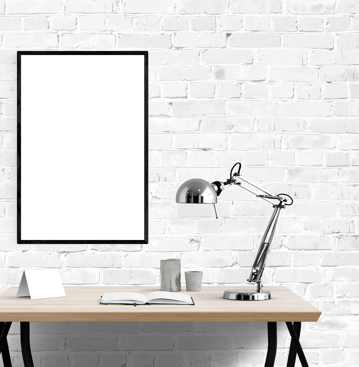 Framed prints hung above a desk alongside stacked books and a small lamp