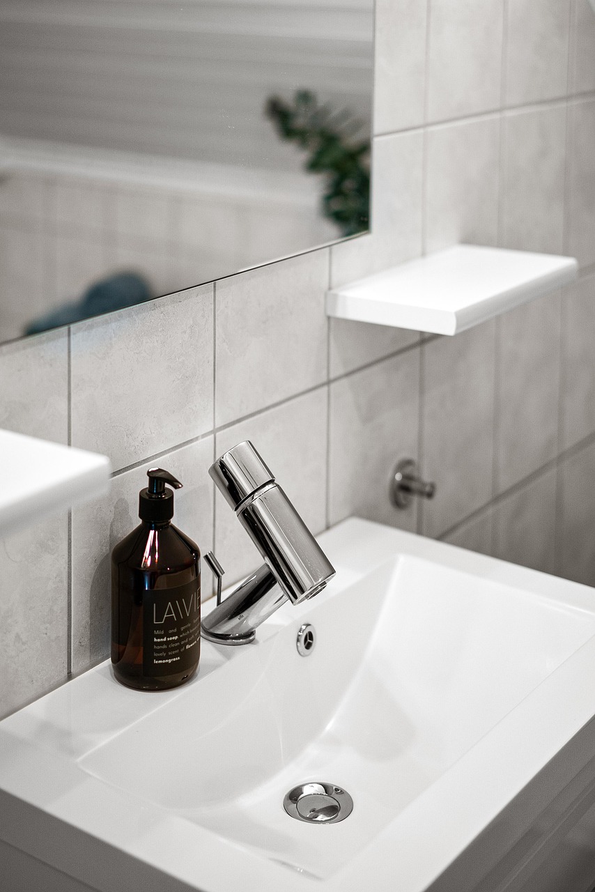 Bathroom vanity styled with a round mirror and warm wall sconces